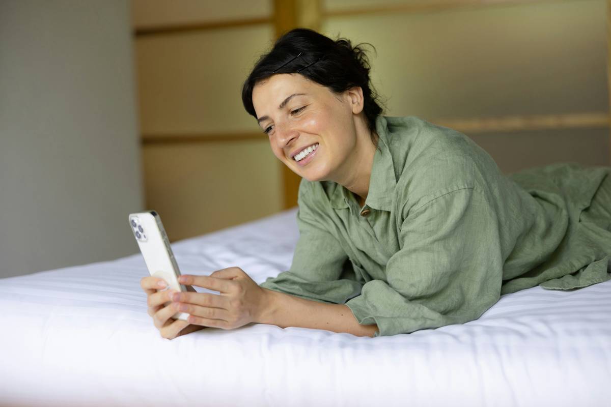 Man sitting cross-legged on his bed wearing headphones, eyes closed, listening to hypnosis session